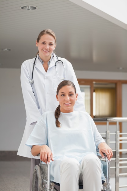 Doctor sonriente al lado de un paciente en una silla de ruedas