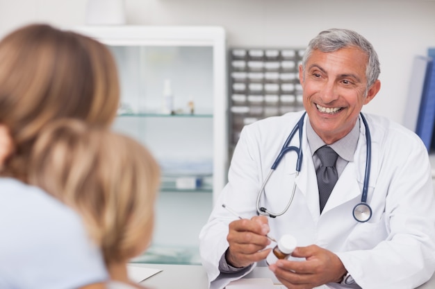 Doctor sonriente escribiendo en un cuadro de drogas