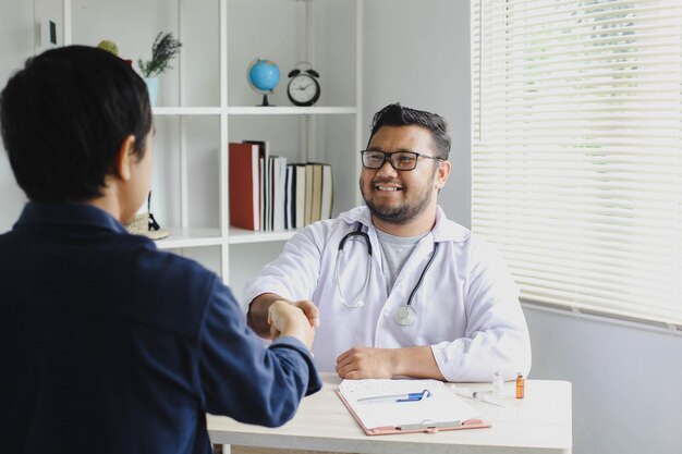 El doctor sonriente feliz saluda a su paciente estrechándole la mano