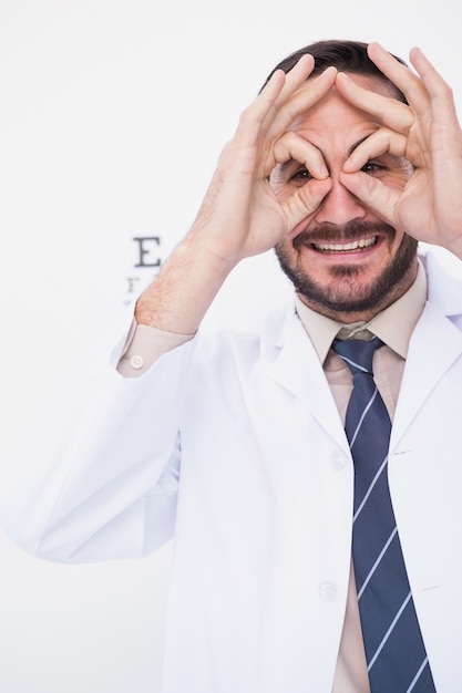 Doctor sonriente formando anteojos con sus manos