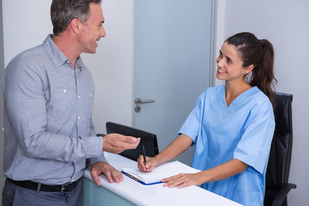 Foto doctor sonriente y paciente hablando en el escritorio