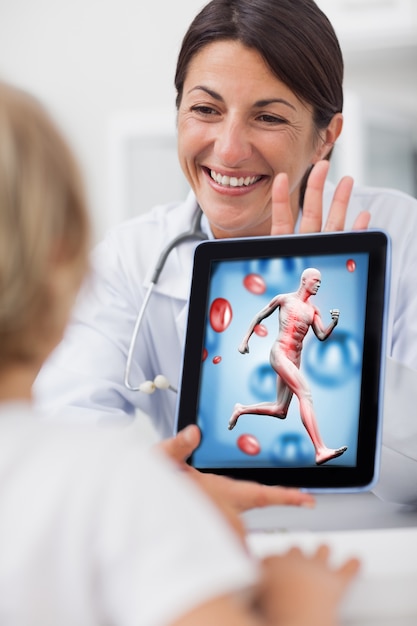 Doctor sonriente que muestra una tableta a un niño