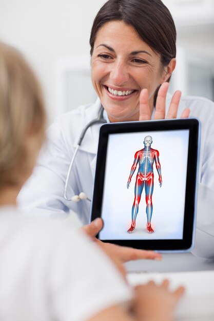 Doctor sonriente que muestra una tableta a un niño