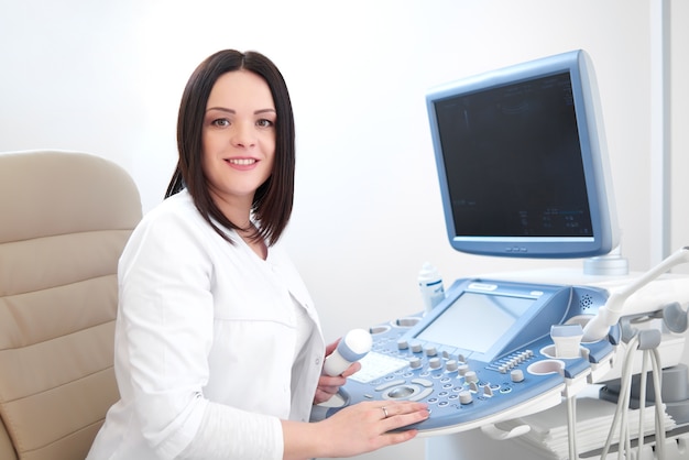 Doctor sonriente que usa el equipo y la computadora del ultrasonido.