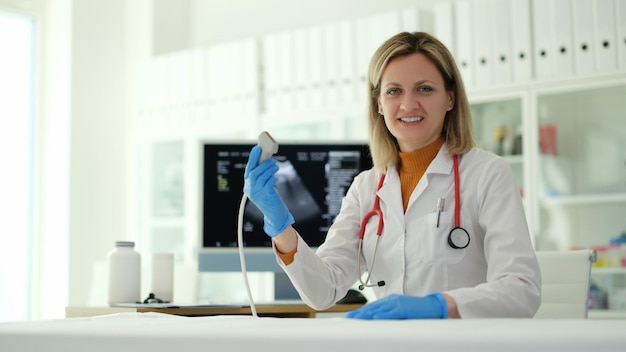 Doctor sonriente con sonda de ultrasonido en la clínica