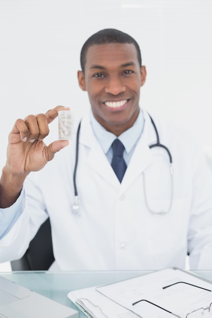 Doctor sonriente sosteniendo una botella de prescripción en consultorio médico