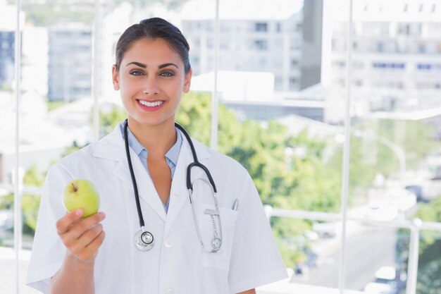 Doctor sonriente sosteniendo una manzana verde