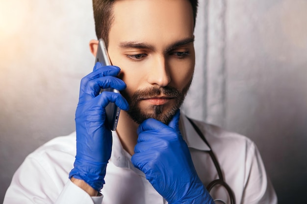 Doctor sostenga el teléfono hablando y mirando a un lado