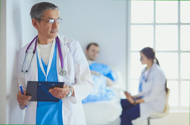 Doctor sosteniendo una carpeta frente a un paciente y un médico