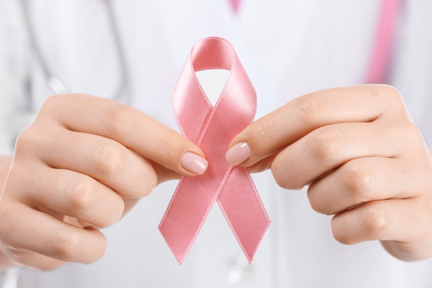 Doctor sosteniendo cinta rosa, primer plano. Concepto de concienciación sobre el cáncer de mama