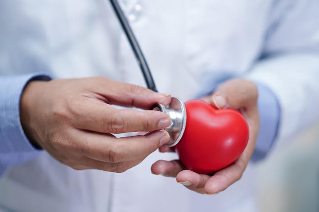 Doctor sosteniendo corazón rojo en su mano en el hospital