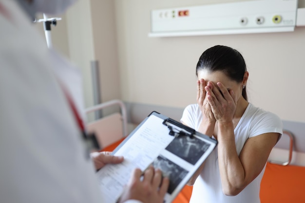 Doctor sosteniendo documentos frente a paciente llorando en la clínica de apoyo psicológico para personas