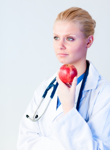Doctor sosteniendo una manzana con enfoque en persona