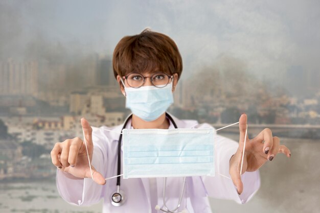 Doctor sosteniendo la máscara para proteger el humo y la contaminación. Bangkok, Tailandia