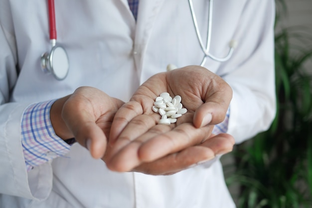 Doctor sosteniendo la píldora médica en la palma de la mano