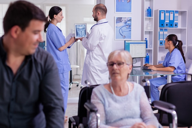 Doctor sosteniendo la radiografía del paciente explicando el diagnóstico a la enfermera en la sala de espera