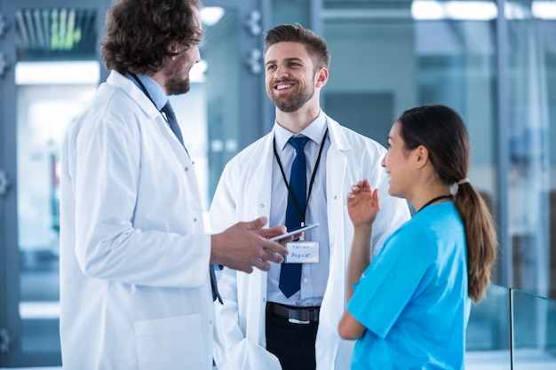 Doctor sosteniendo tableta digital teniendo una discusión con colegas