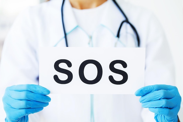 Doctor sosteniendo una tarjeta con el símbolo SOS