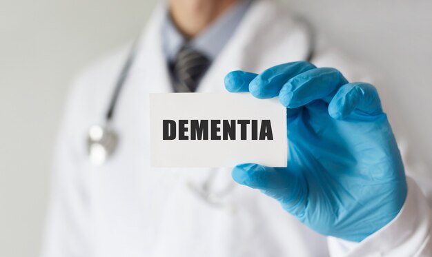 Foto doctor sosteniendo una tarjeta con texto dementia, concepto médico