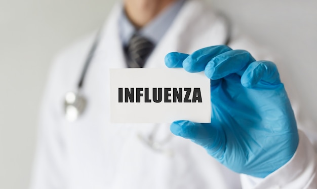 Doctor sosteniendo una tarjeta con texto INFLUENZA, concepto médico