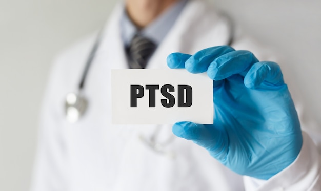 Doctor sosteniendo una tarjeta con texto PTSD, concepto médico