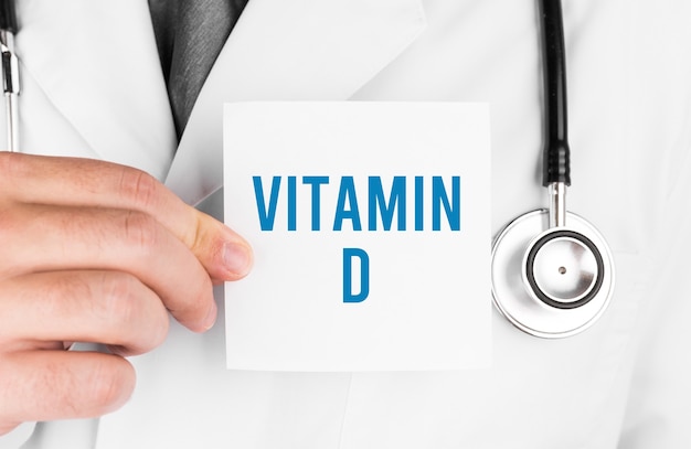 Doctor sosteniendo una tarjeta con texto VITAMINA D, concepto médico