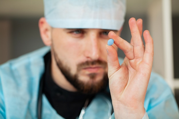 Doctor sostiene una pastilla para la salud de los hombres.