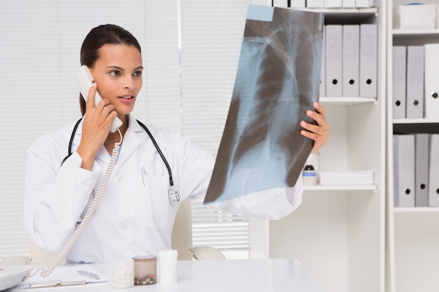 Doctor en el teléfono analizando los resultados de la radiografía