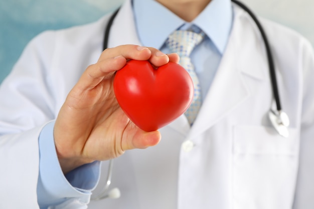 Doctor tiene corazón contra la superficie azul, primer plano