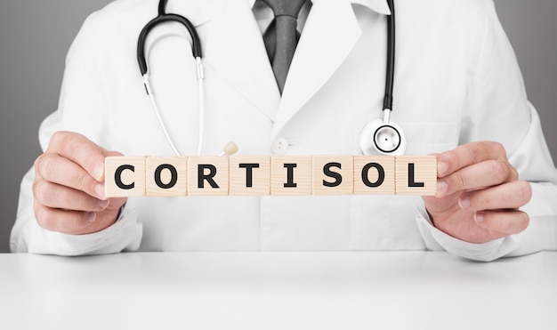 Doctor tiene cubos de madera en sus manos con texto CORTISOL