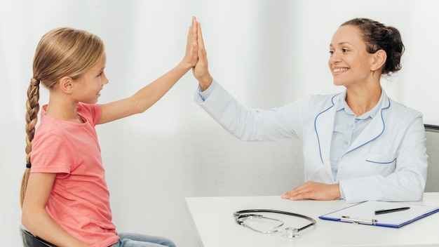 Foto doctor de tiro medio y niña chocando los cinco