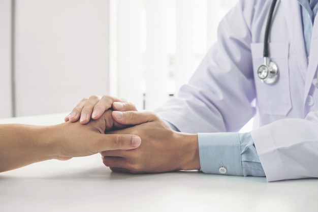 doctor tocando la mano del paciente para el estímulo y la empatía en el hospital