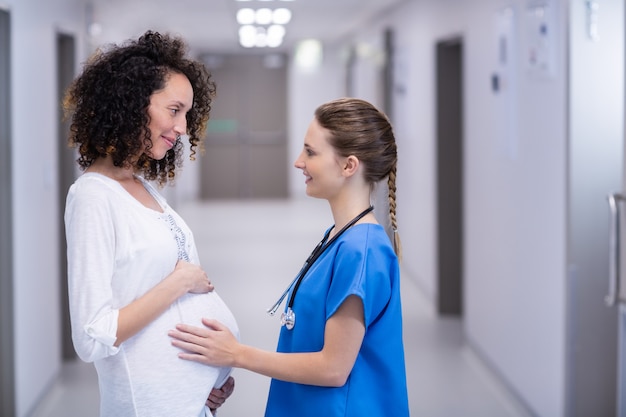 Doctor tocando el vientre de la mujer embarazada en el pasillo