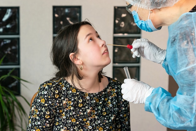 El doctor toma un hisopo de la nariz de la niña para una prueba de coronavirus