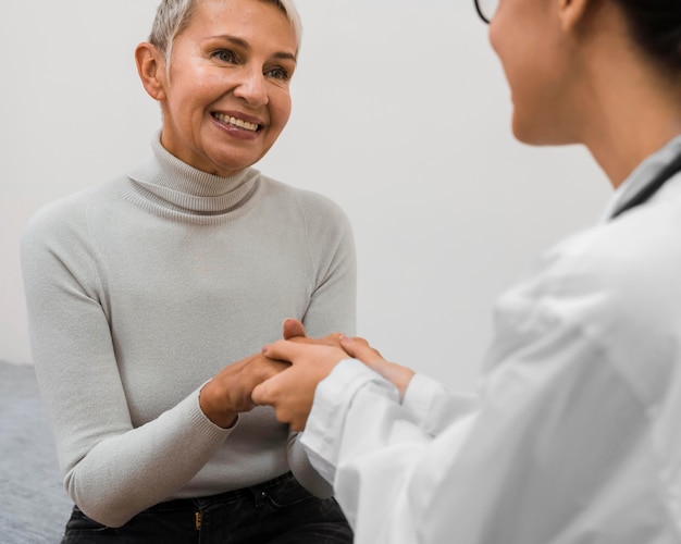 Foto doctor tomados de la mano con paciente feliz