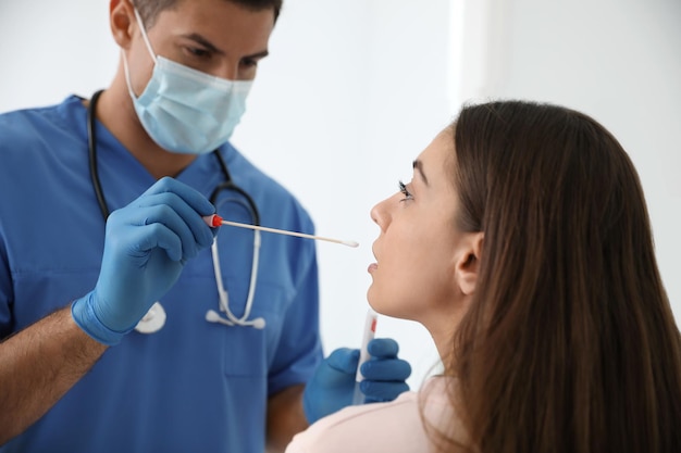 Doctor tomando muestra para prueba de ADN de mujer en clínica