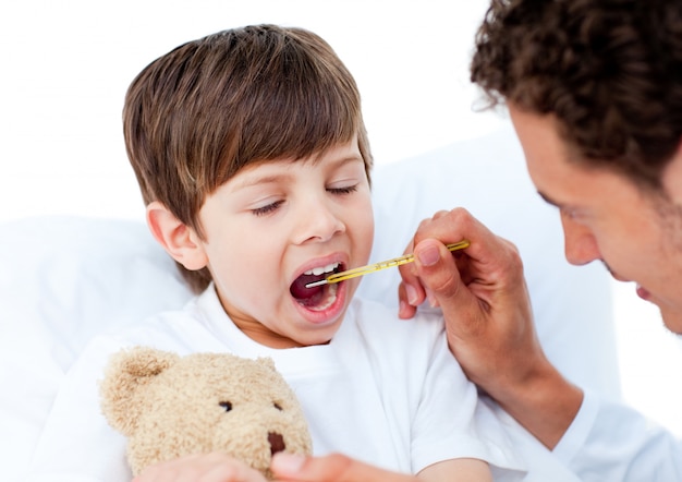 Doctor tomando la temperatura del niño pequeño