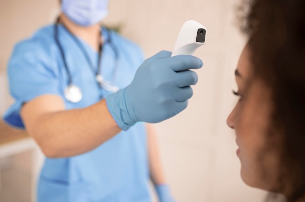 Foto doctor tomando la temperatura de un paciente