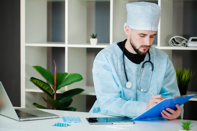 El doctor trabaja en una mesa en la oficina de la clínica.