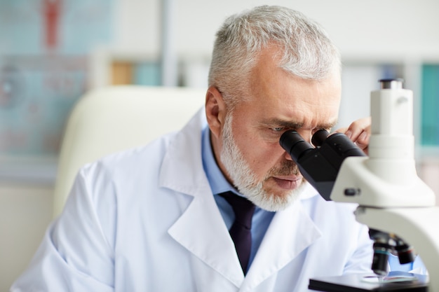 Doctor trabajando con microscopio en la oficina