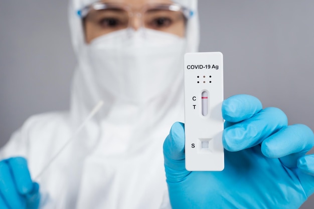 Doctor en traje de EPP con resultado negativo de prueba de Coronavirus (Covid-19) con el kit de prueba rápida de antígeno (ATK)