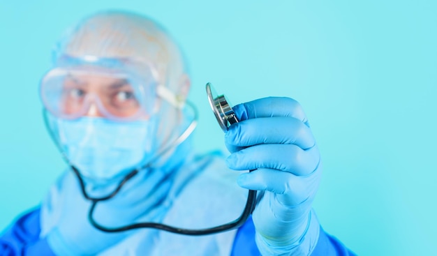 Doctor en traje protector y máscara médica con clínica de hospital de publicidad de estetoscopio