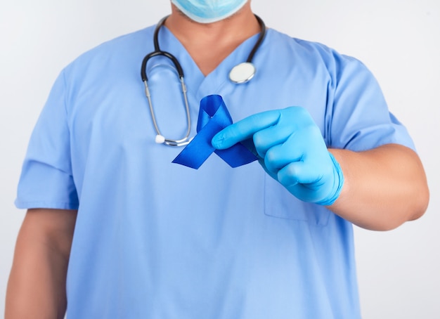 Doctor en uniforme azul y guantes de látex estériles sostiene una cinta azul oscuro