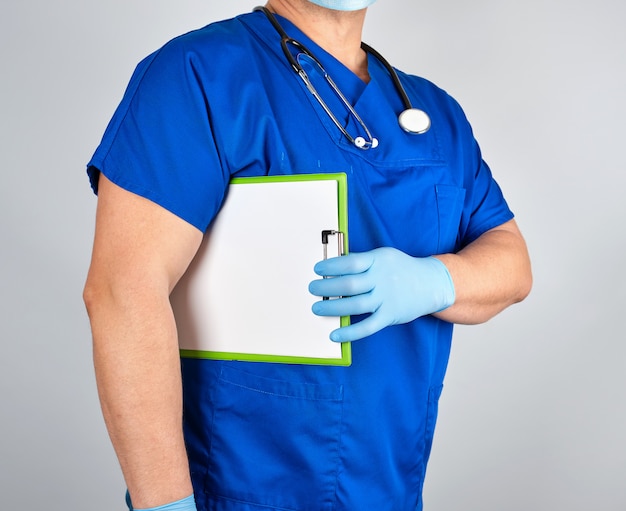 Doctor en uniforme azul y guantes de látex estériles tiene portapapeles