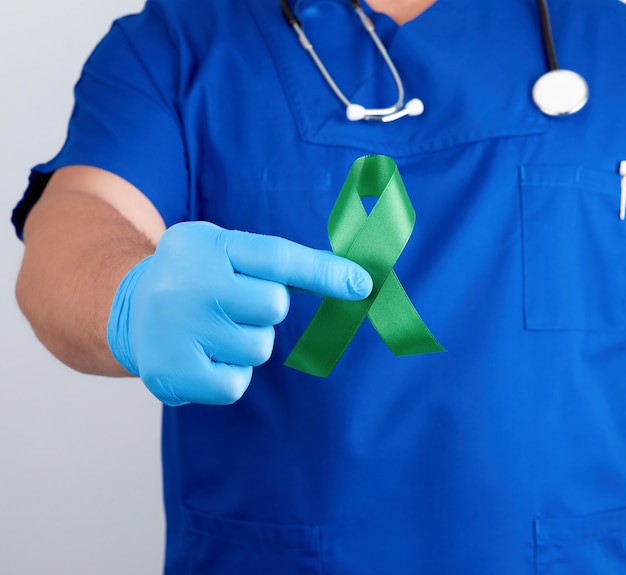 Doctor en uniforme azul y guantes de látex sostiene una cinta verde