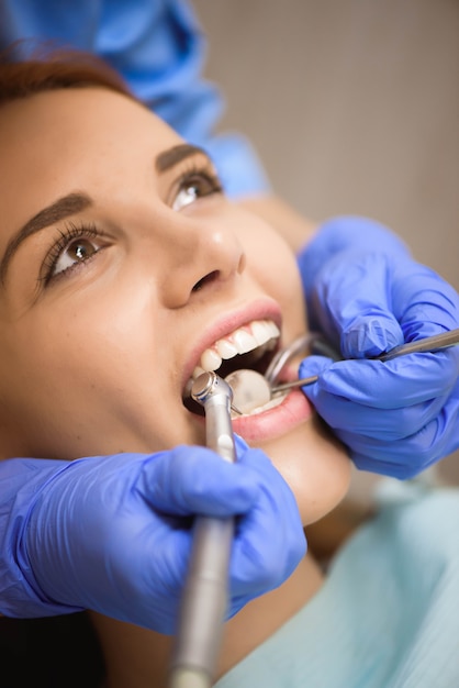 Foto doctor en uniforme revisando los dientes del paciente femenino en clínica dental