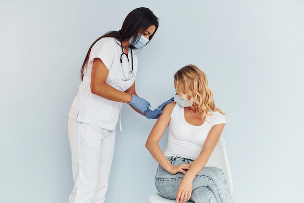 Doctor en uniforme vacunando a la mujer