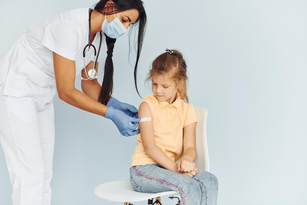 Doctor en uniforme vacunando a la niña