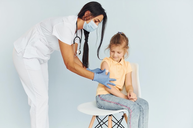 Doctor en uniforme vacunando a la niña