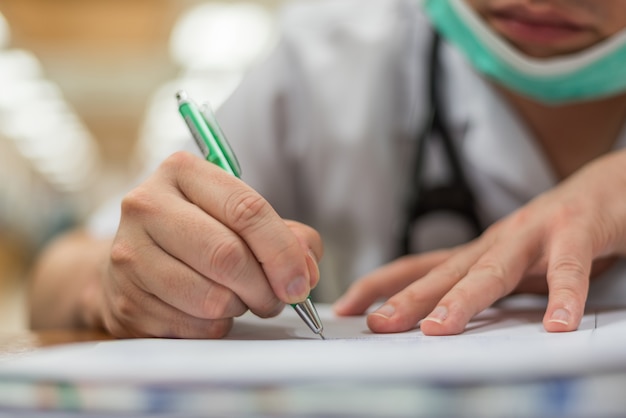 El doctor usa un bolígrafo que escribe sobre atención médica y remedio en papel o documento de prescripción